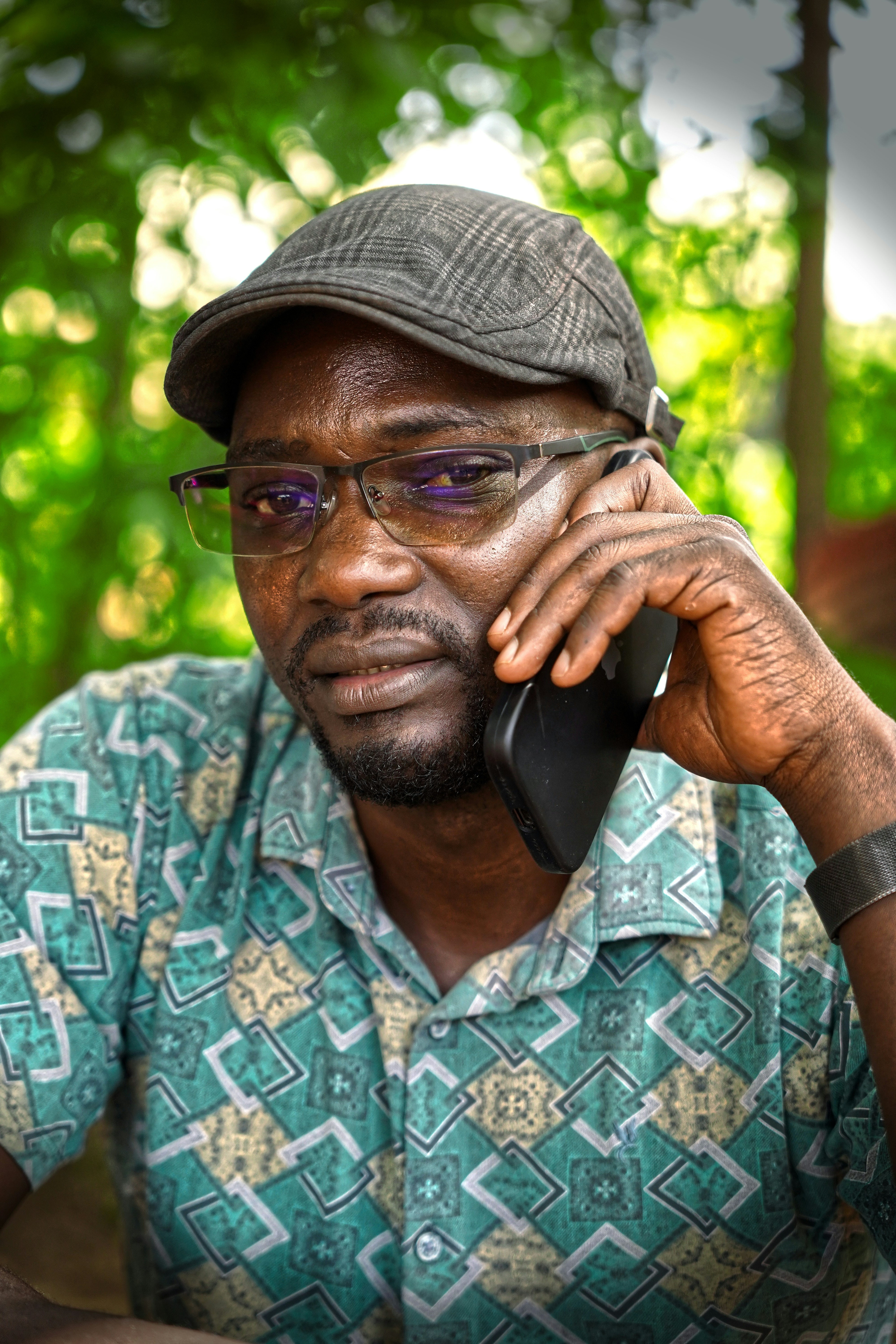 Hombre con gorra y gafas hablando por teléfono.