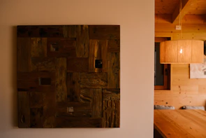 Wooden art piece hangs on a wall above a table.