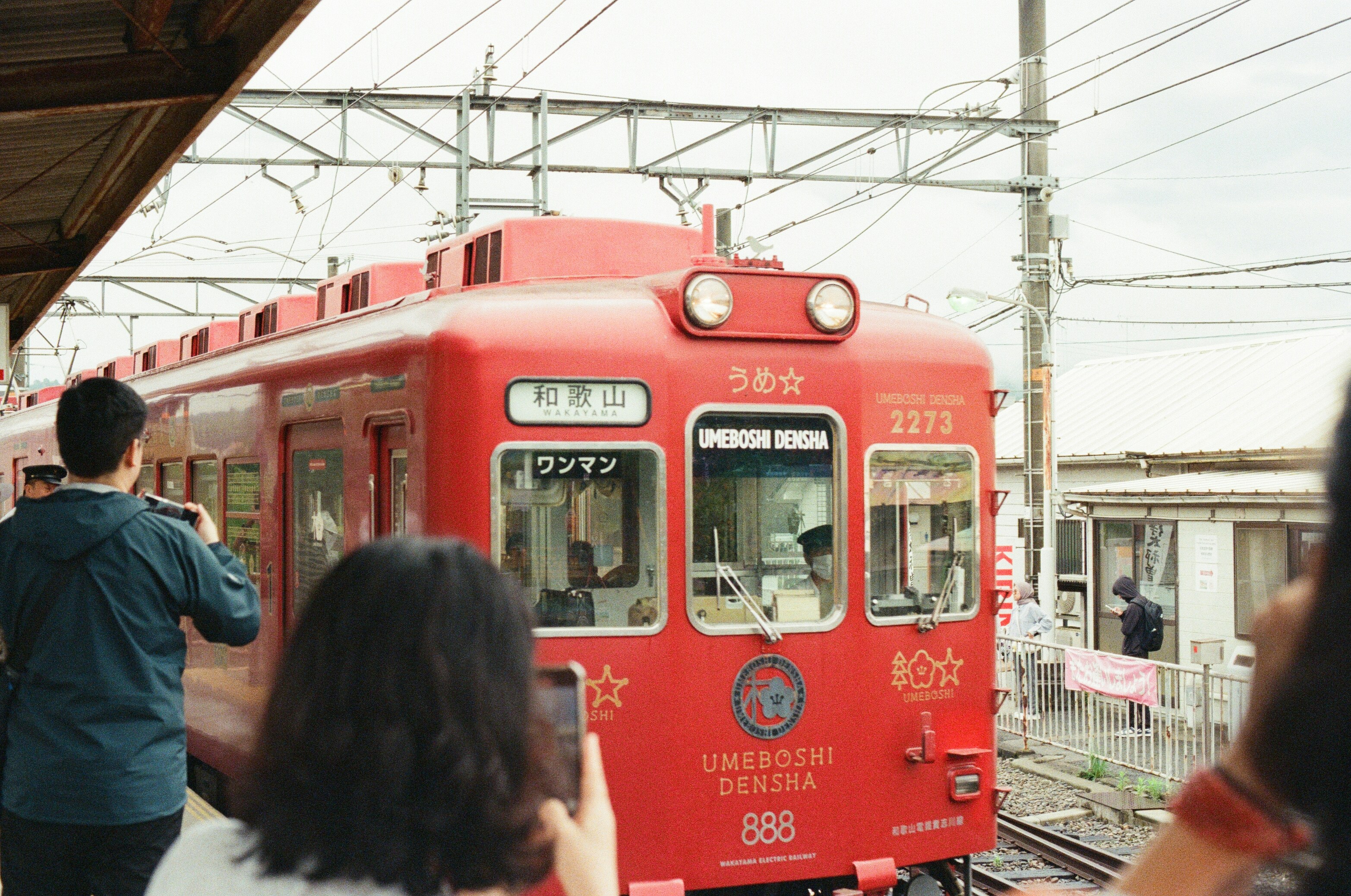 Red train at a station with people taking photos