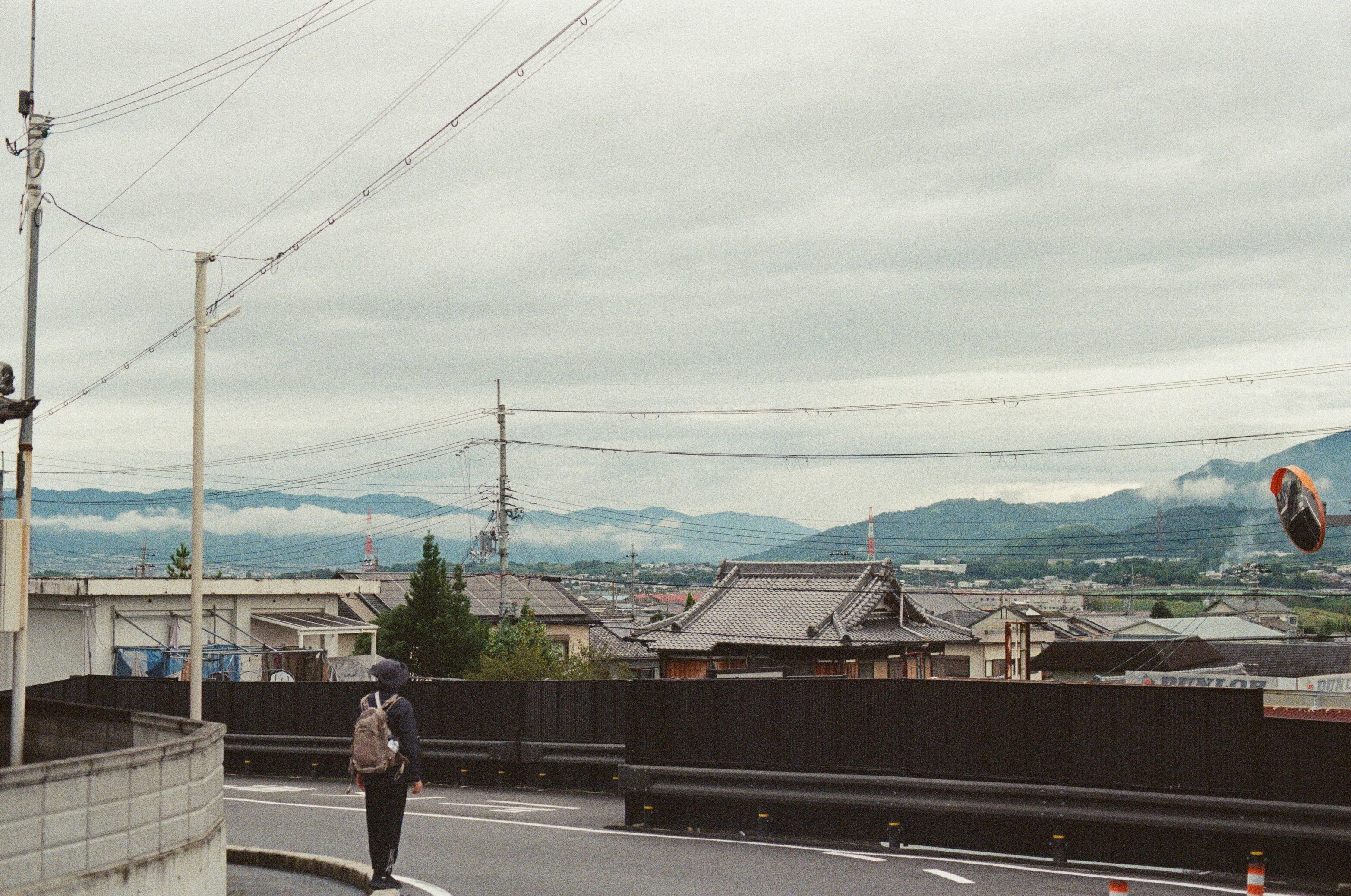 A person stands on a street overlooking a town.
