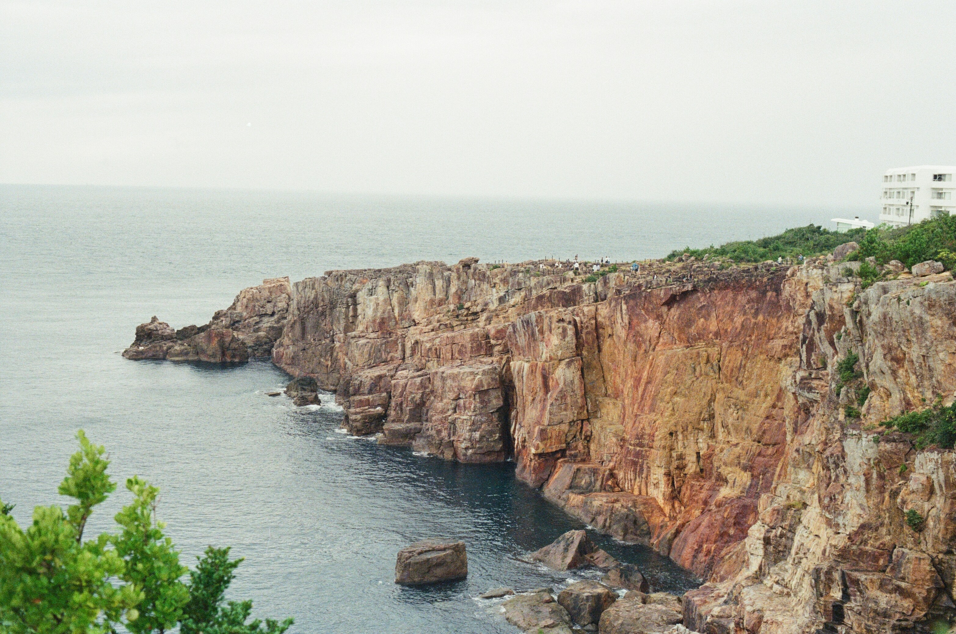 Rugged cliffs meet the ocean under a cloudy sky.
