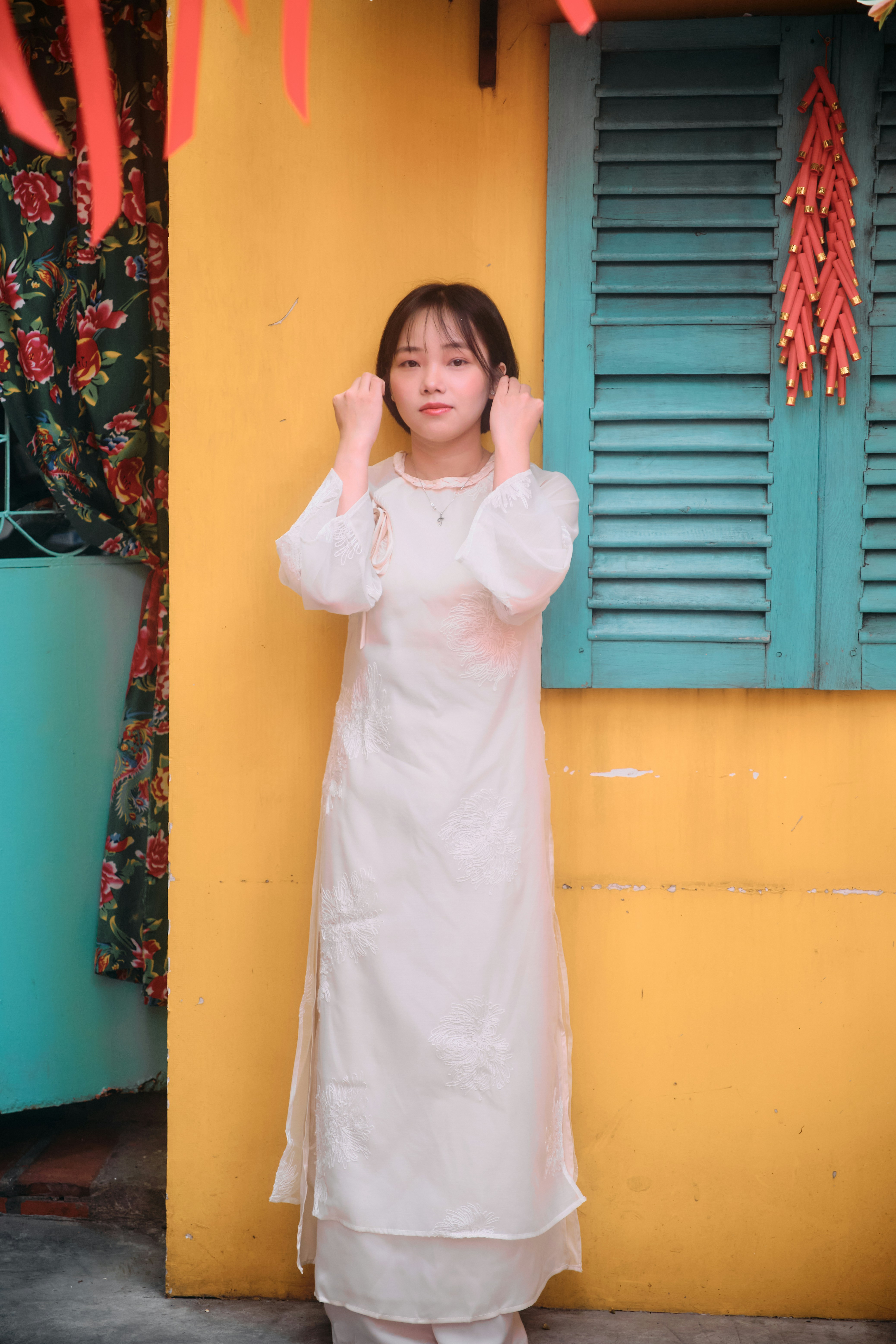 Young woman in white dress by colorful wall