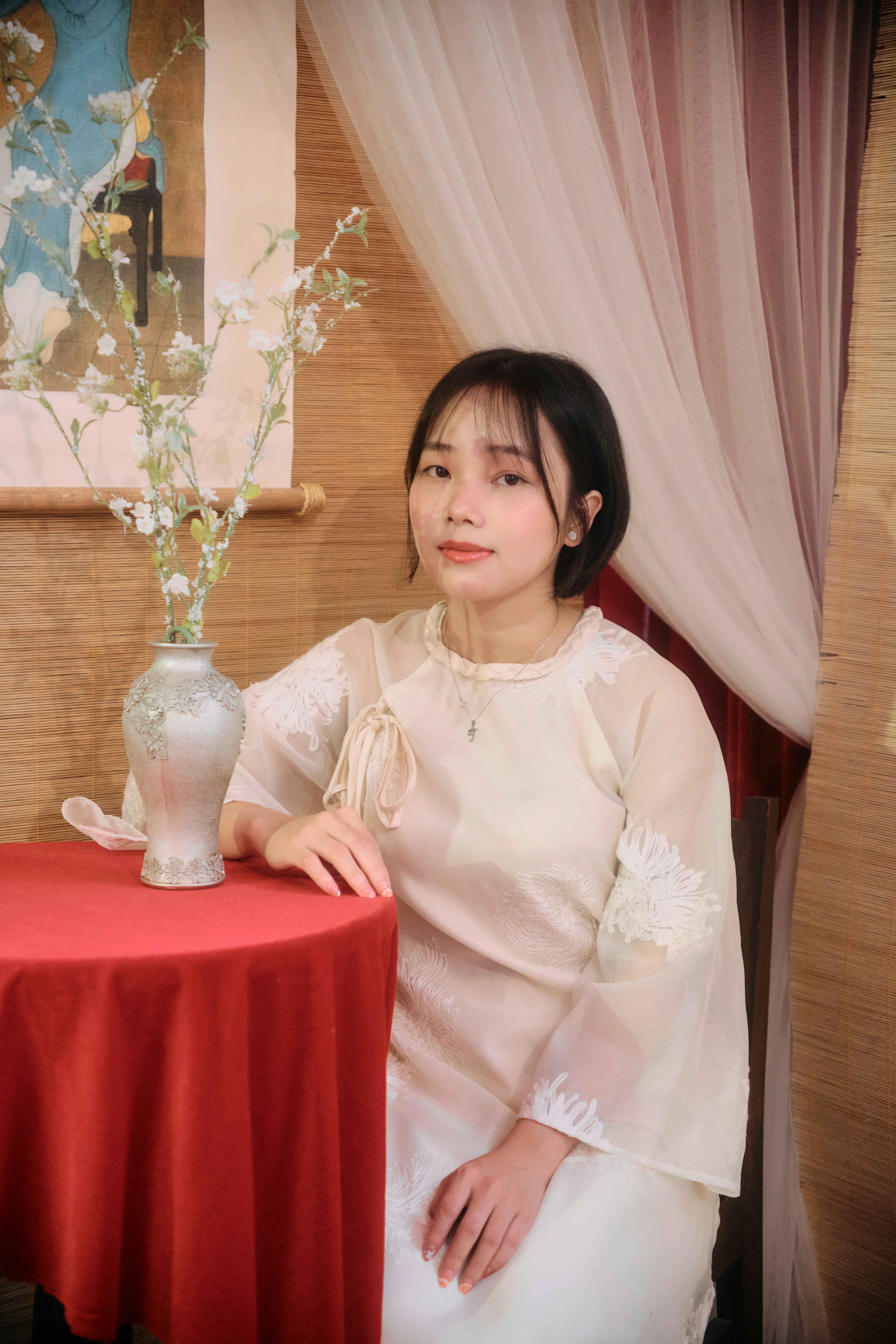 Young woman in traditional dress sits by a red table.