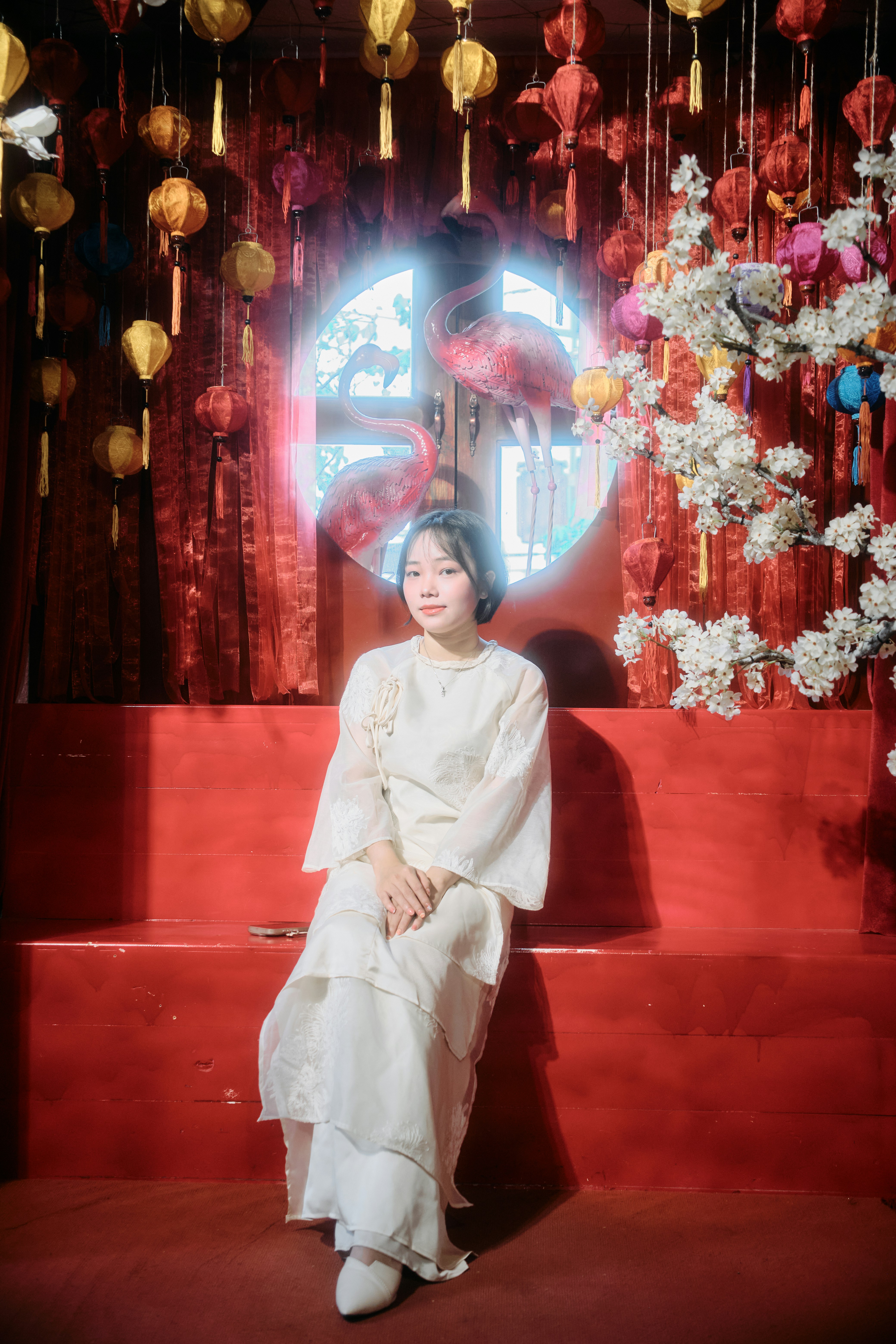 Woman in white dress sits in red room decorated room