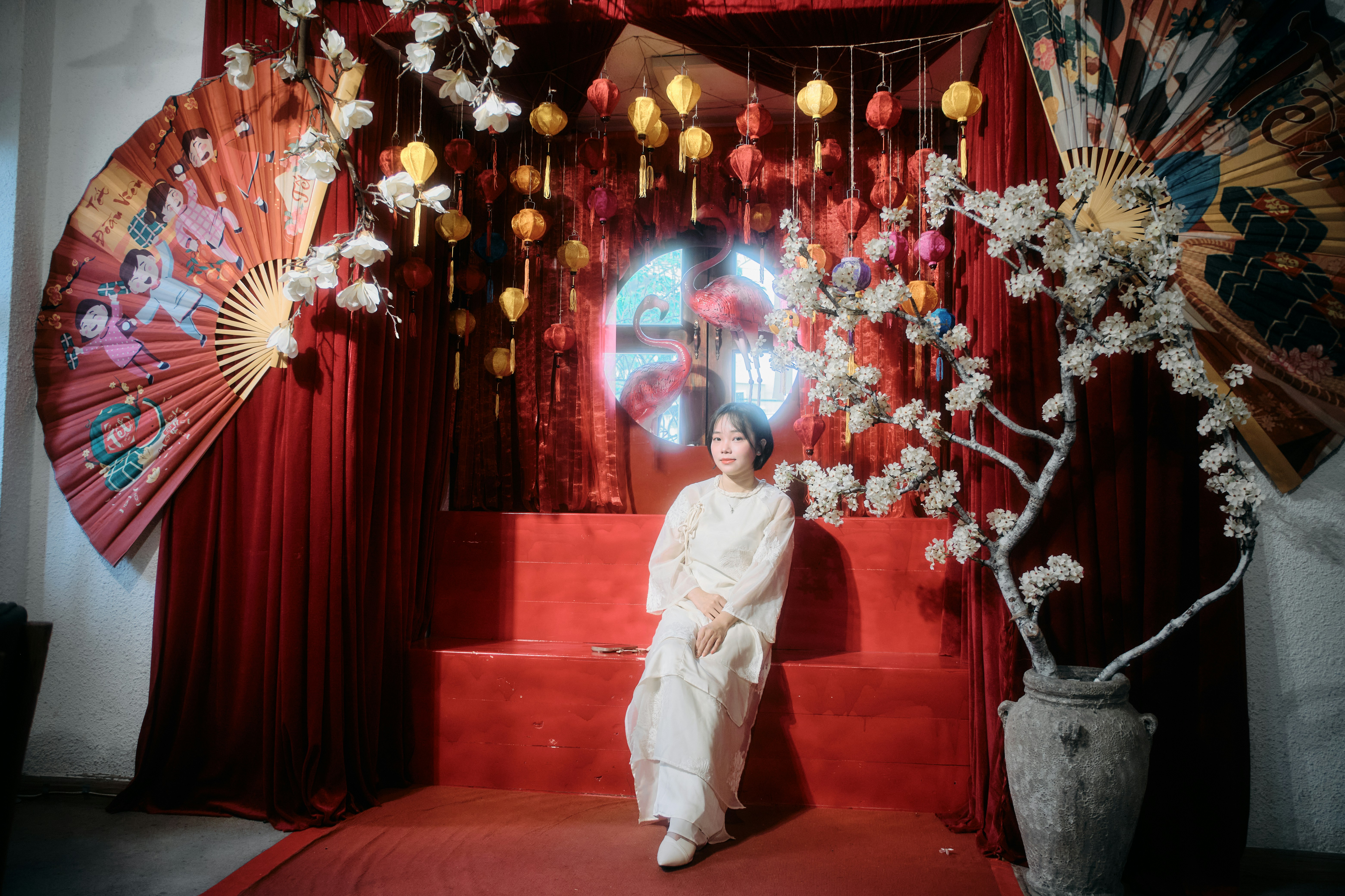Woman in white dress posing against festive red backdrop