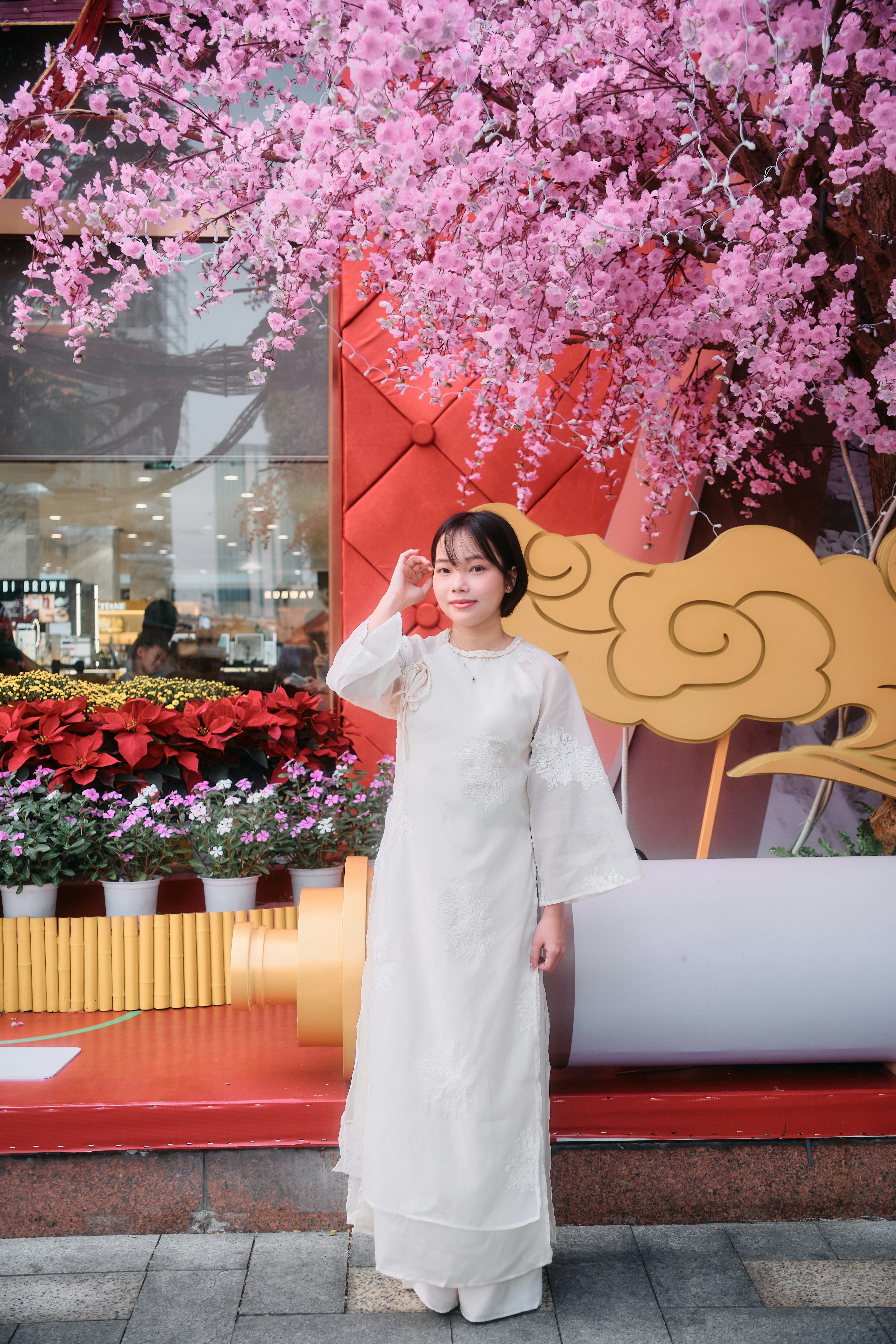 Young woman in white dress under pink blossoms