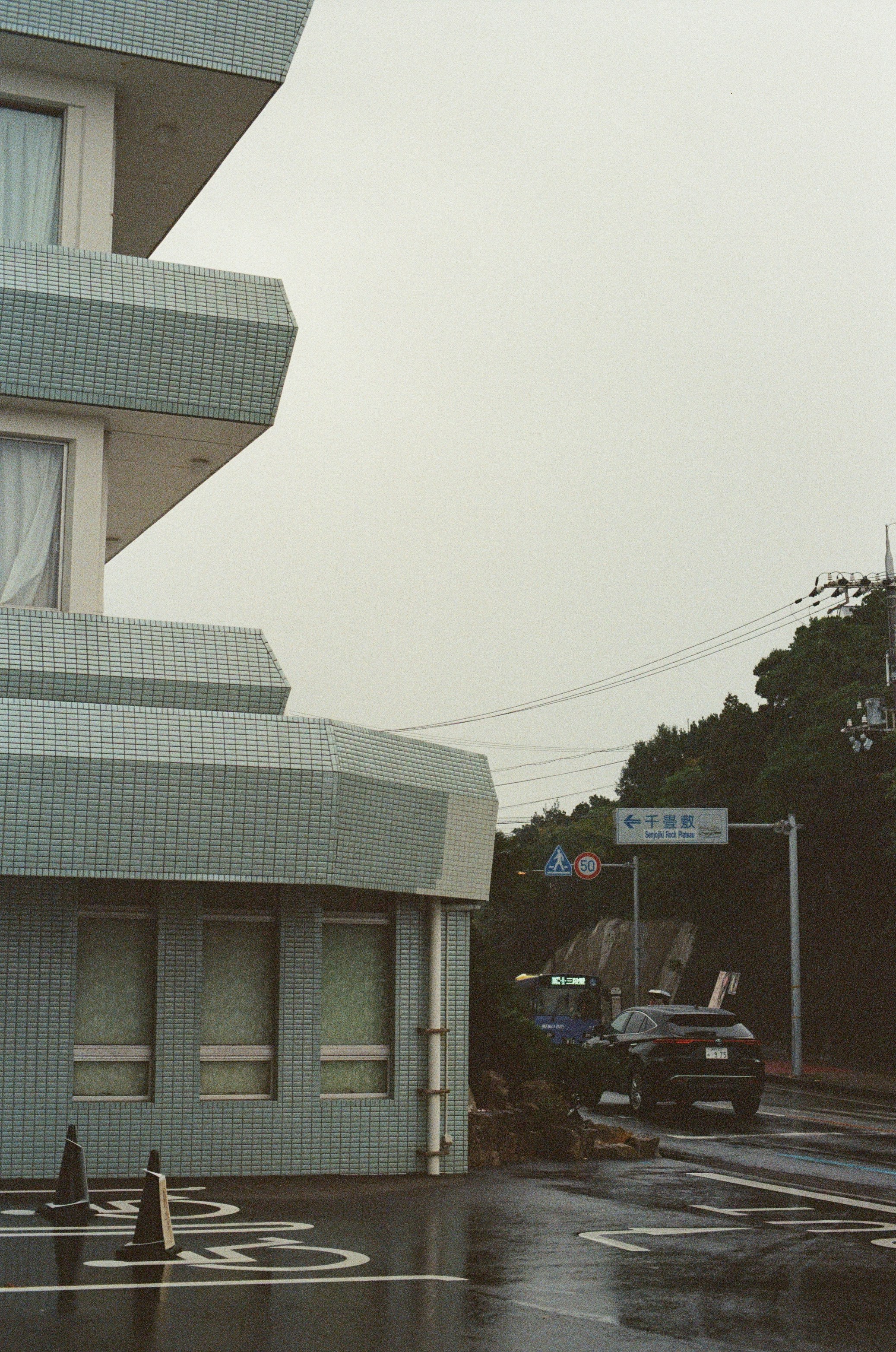 Modern building on a wet street with car.