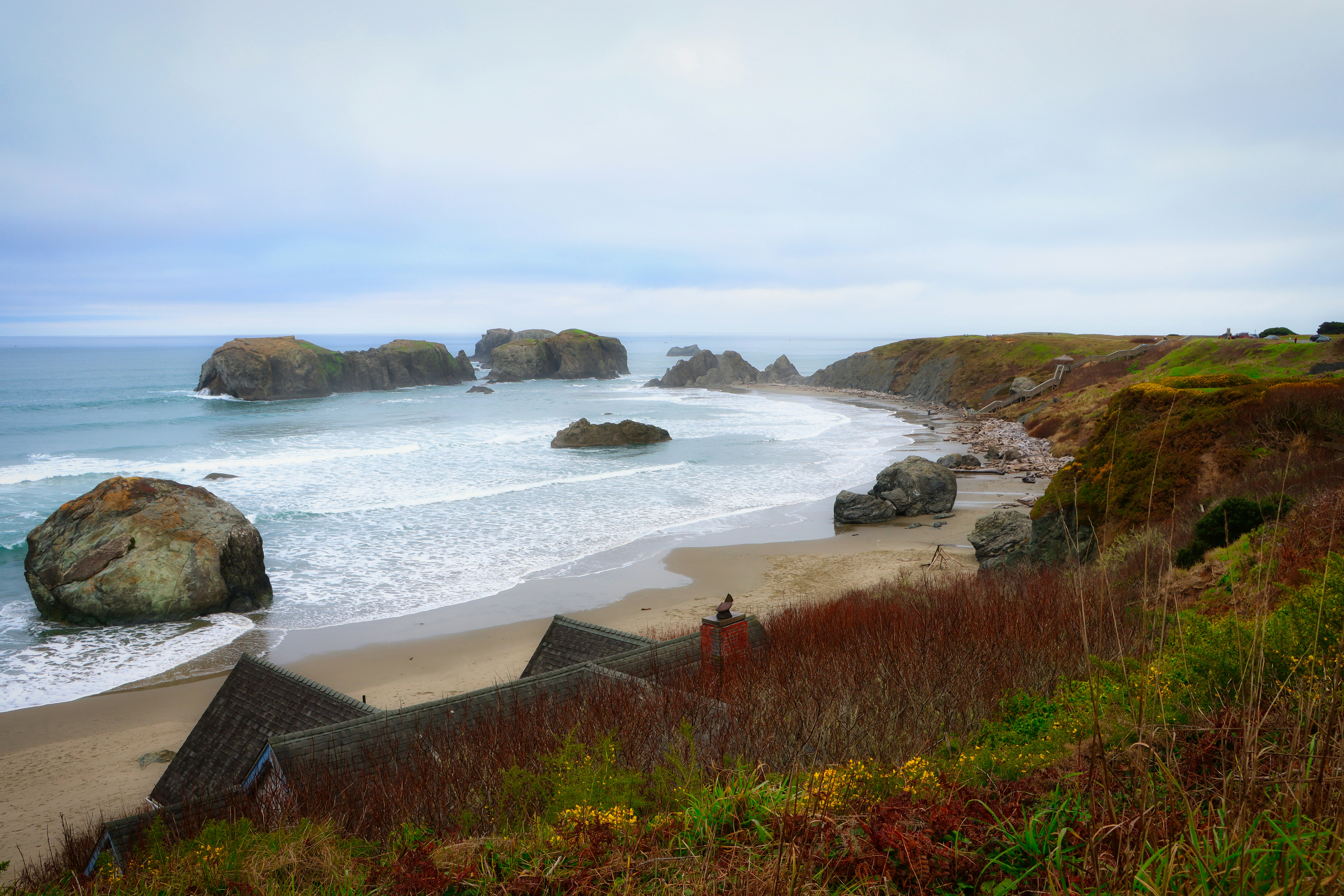 Coastal cliffs with rock formations and a sandy beach.