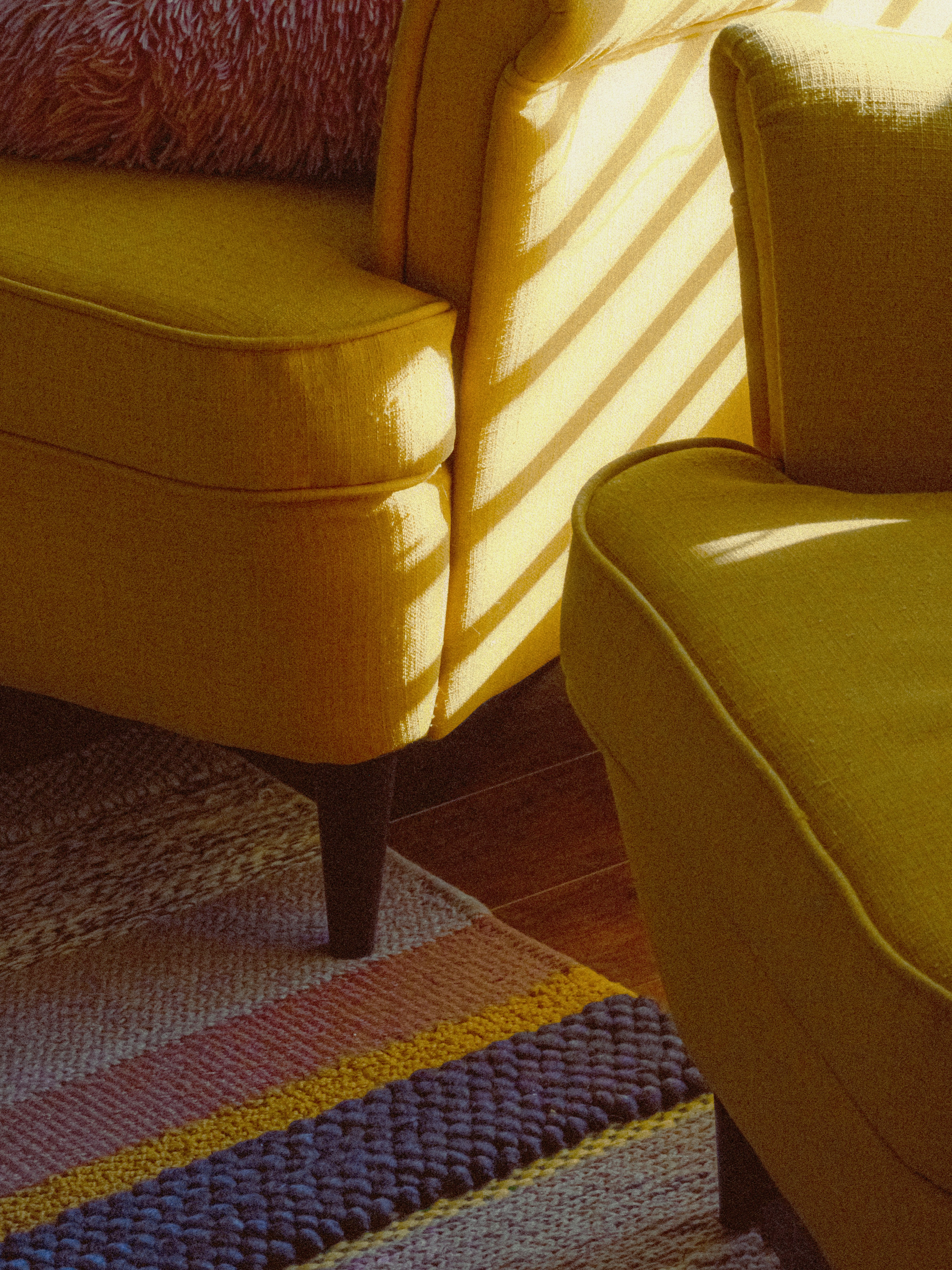 Yellow armchairs with striped rug and sunlight.