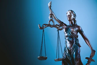 Statue of justice holding scales against blue background