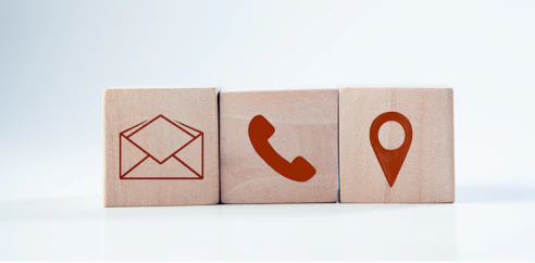Wooden blocks with contact icons: envelope, phone, location.