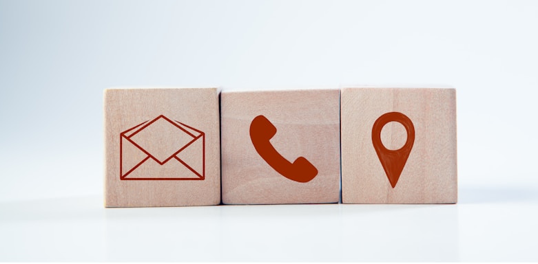 Wooden blocks with contact icons: envelope, phone, location.