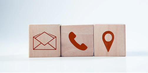 Wooden blocks with contact icons: envelope, phone, location.