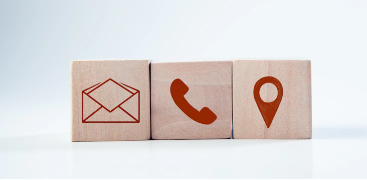 Wooden blocks with contact icons: envelope, phone, location.