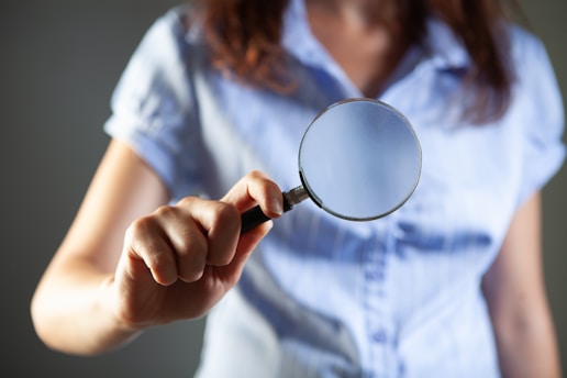 Woman holding a magnifying glass towards the viewer.