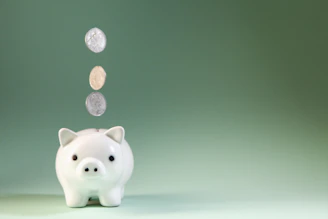 Coins falling into a white piggy bank.
