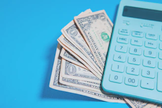 Us dollar bills and a calculator on blue background