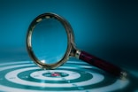 Magnifying glass over a target with bullseye.
