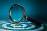 Magnifying glass over a target with bullseye.