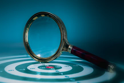 Magnifying glass over a target with bullseye.