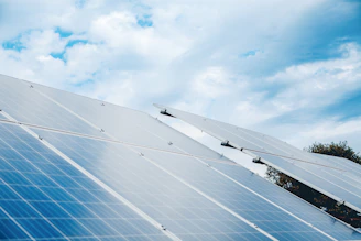 Rows of solar panels under a cloudy sky.
