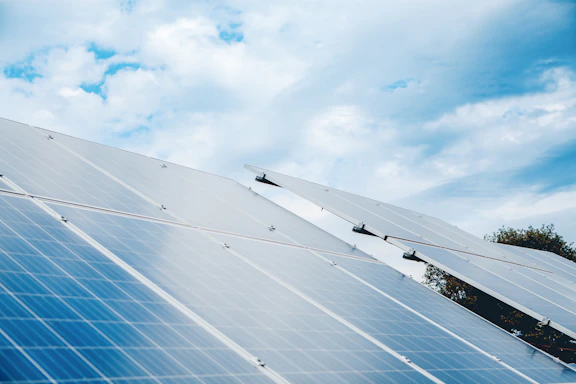 Rows of solar panels under a cloudy sky.