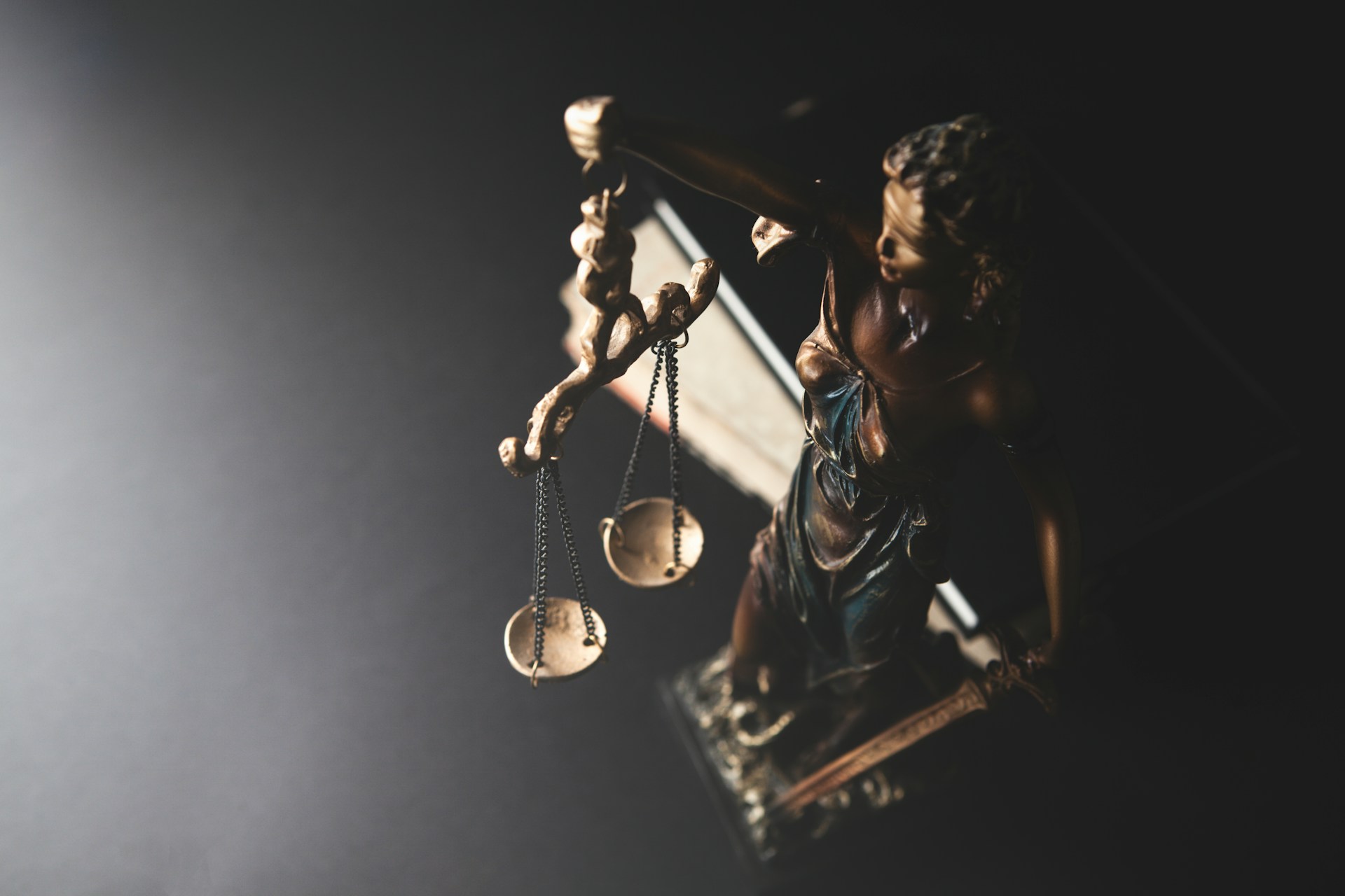 Statue of justice with scales on dark background