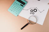 Calculator, magnifying glass, and chart with gears on paper