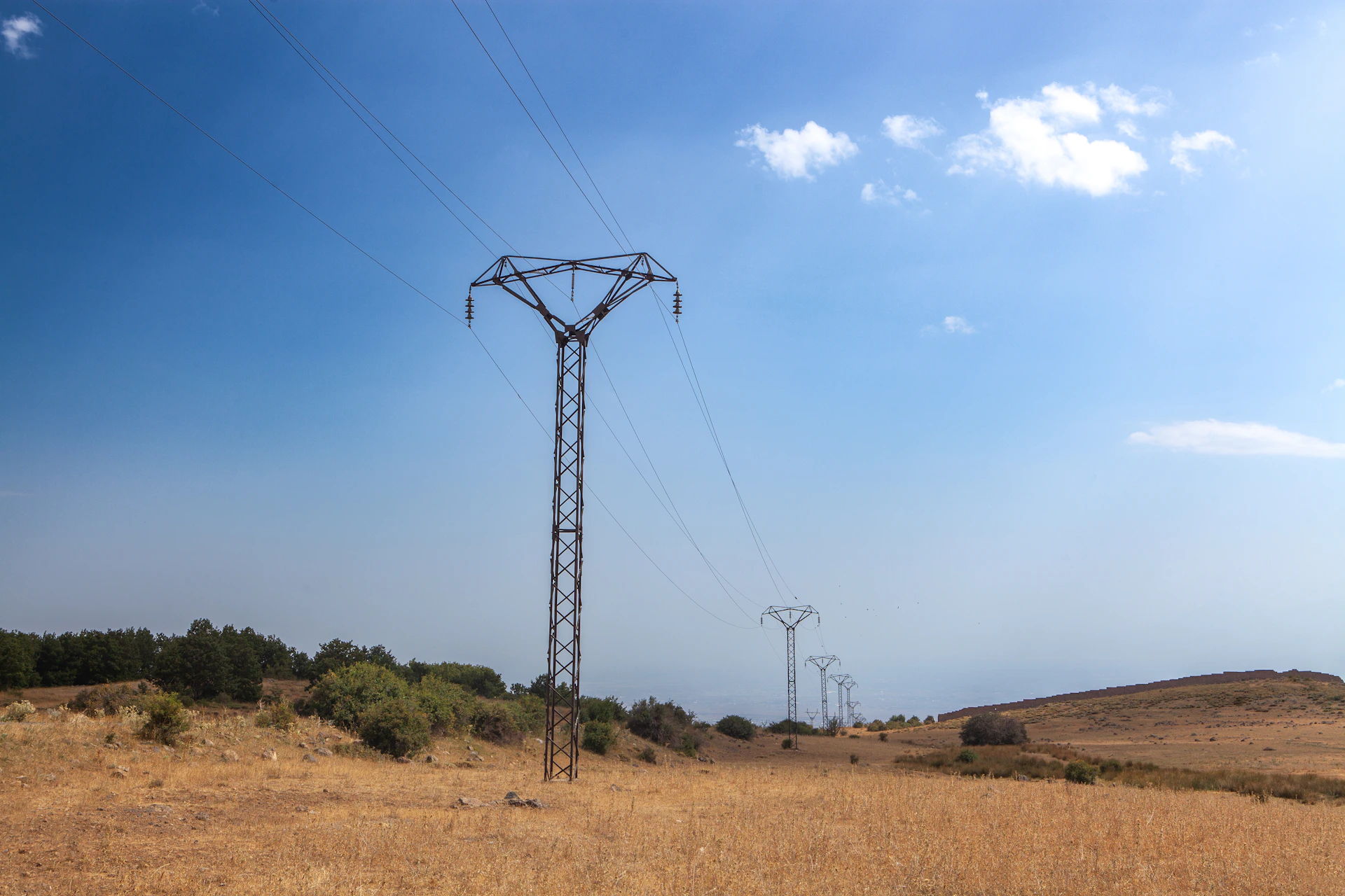 Power lines stretch across a dry, grassy landscape.