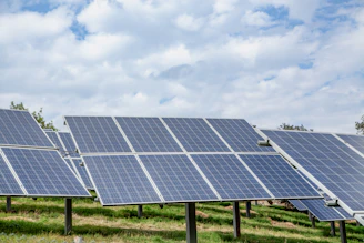 Solar panels in a field under a cloudy sky