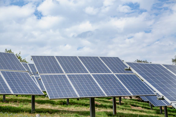 Solar panels in a field under a cloudy sky