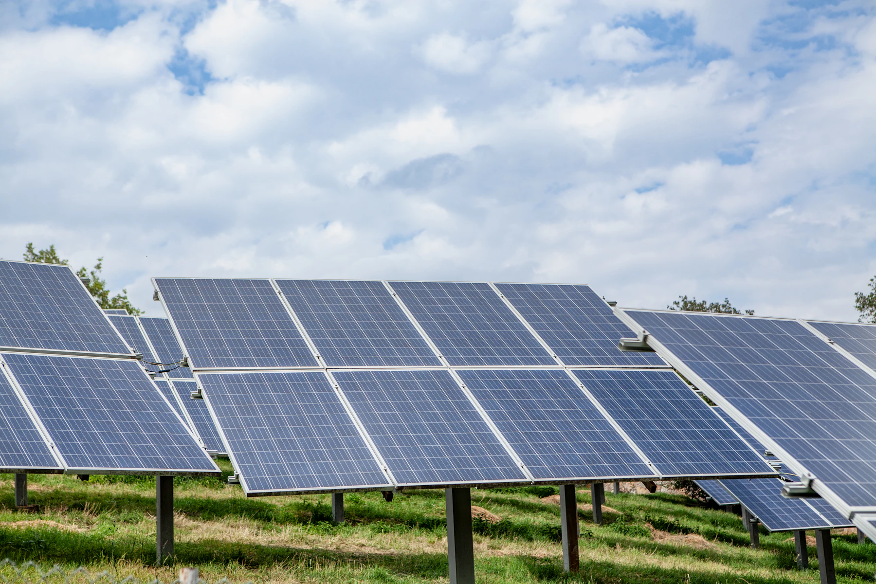 Solar panels installed across an open field under a blue sky
