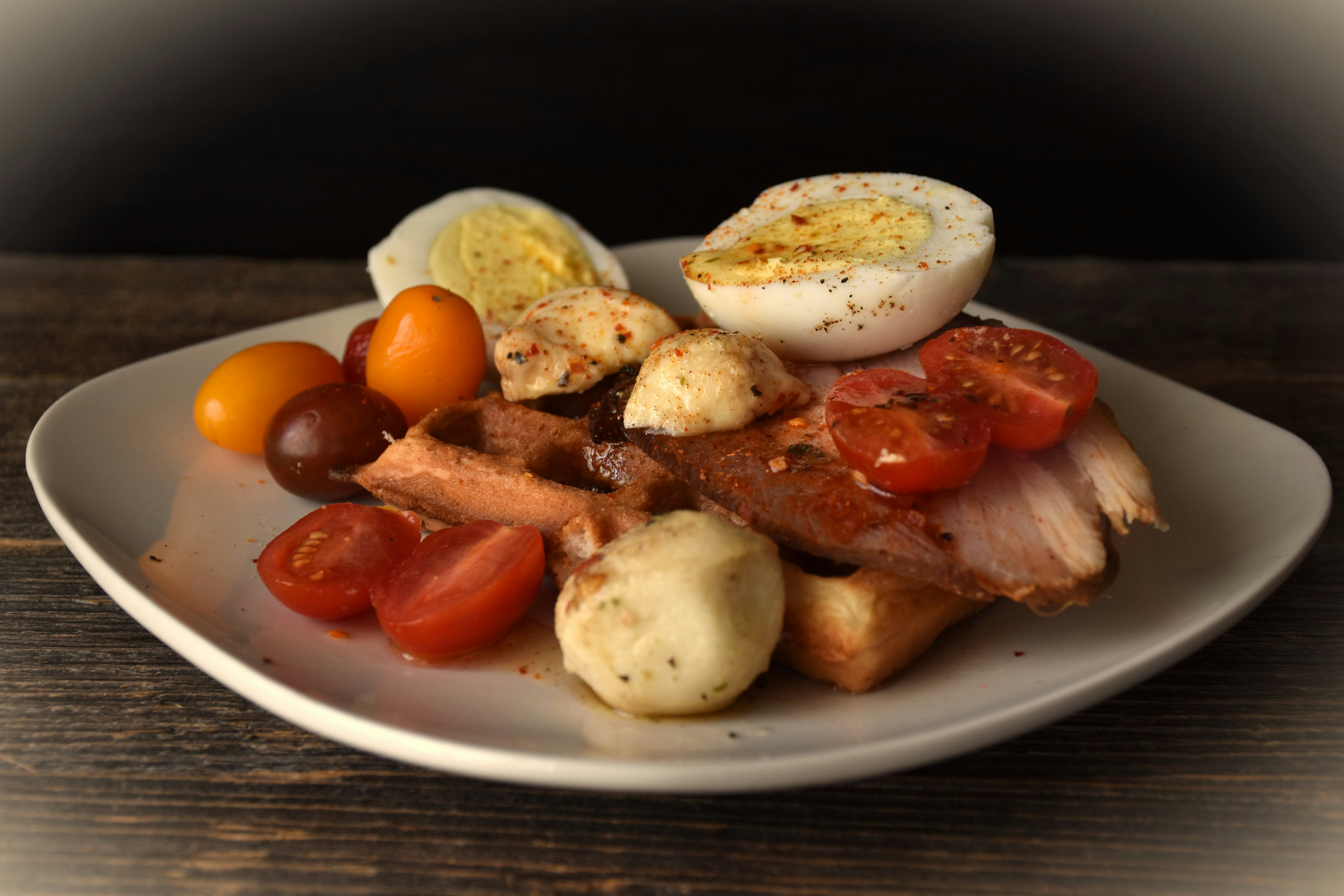 Savory waffle topped with chicken, tomato, and egg.