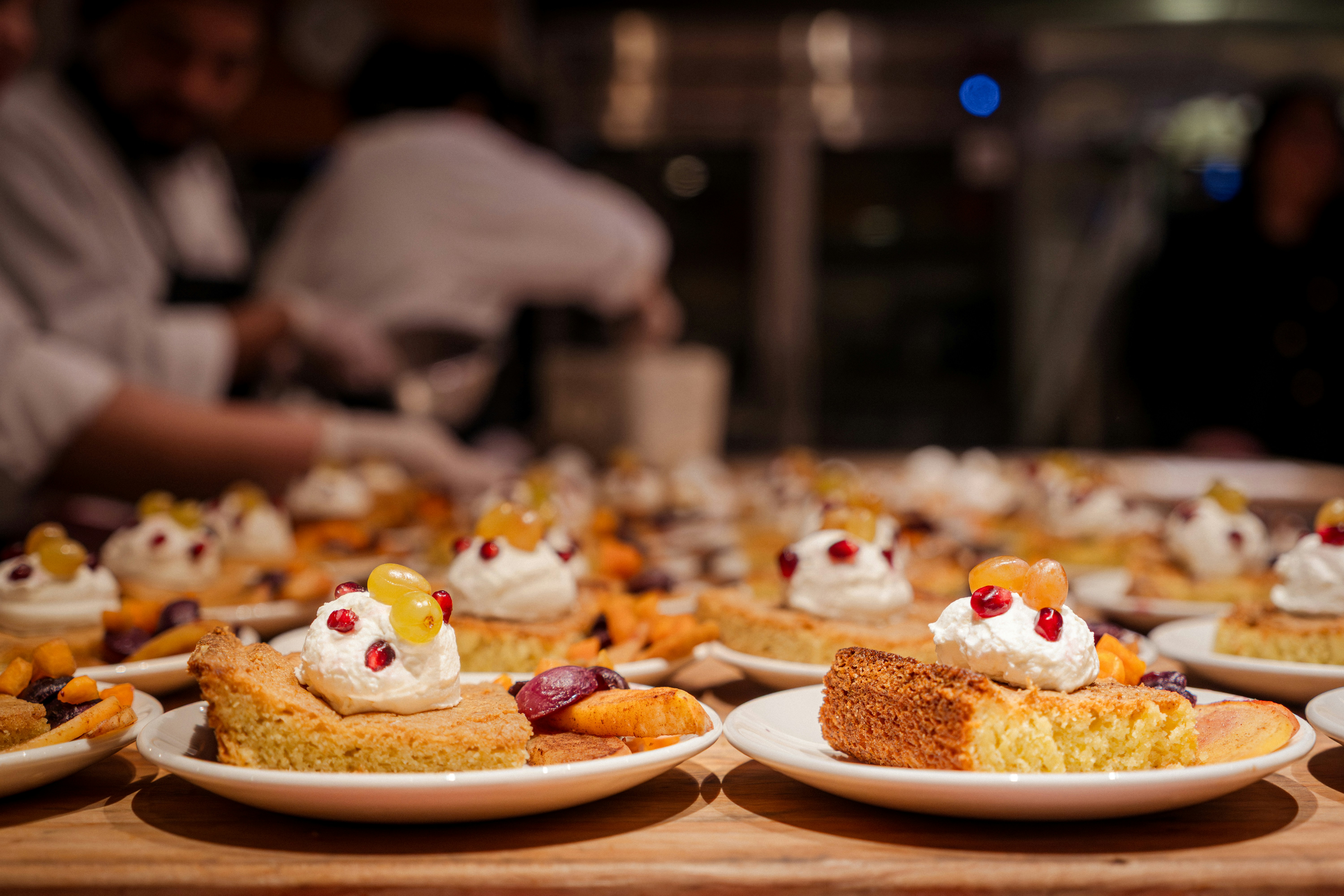 Desserts topped with cream and fruit arranged on plates.