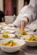 Chef garnishing bowls of food on a counter