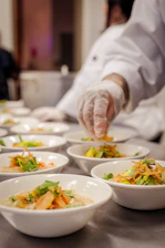 Chef garnishing bowls of food on a counter