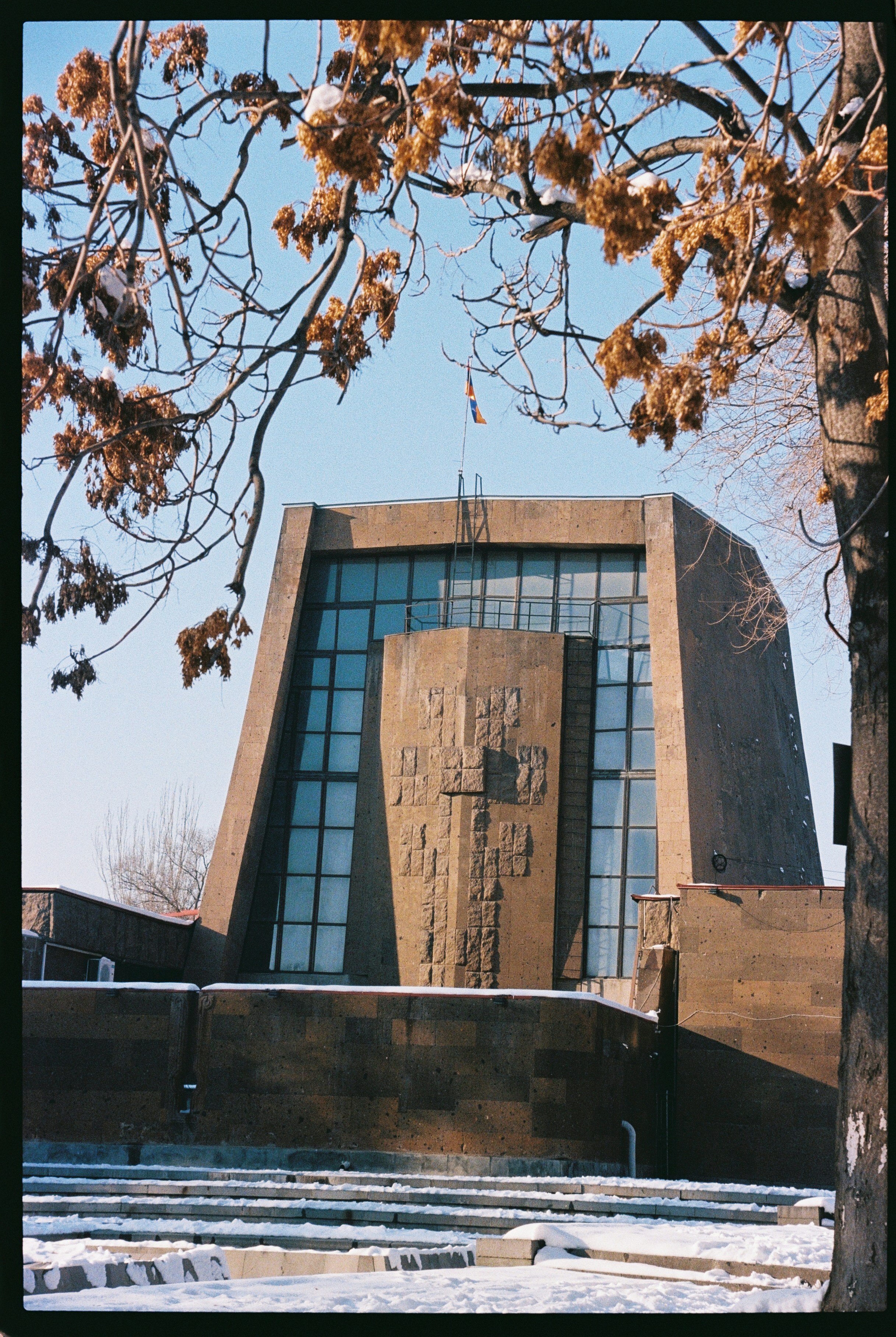 Modern brutalist building with large glass windows and stone facade.