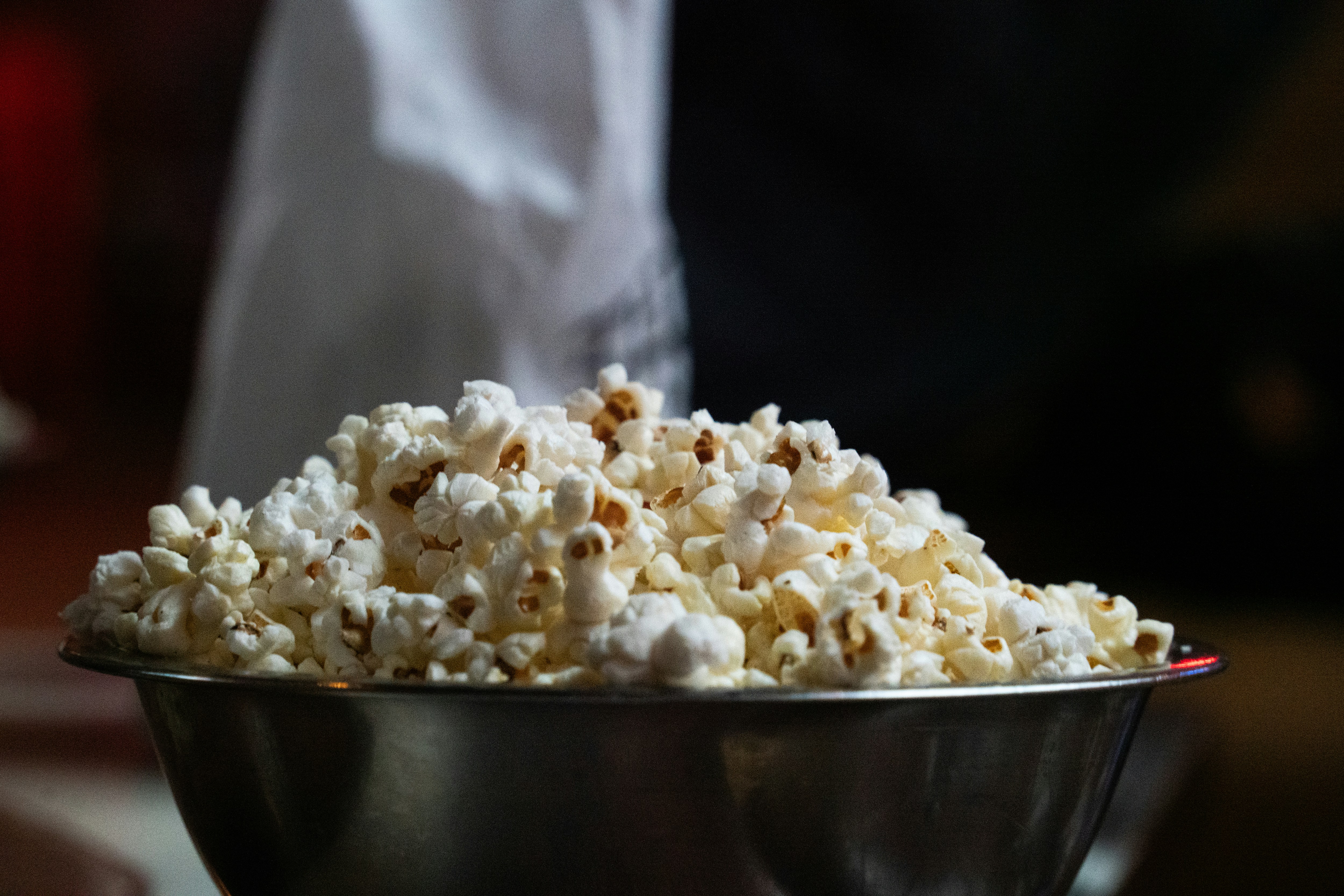 A metal bowl overflowing with freshly popped popcorn