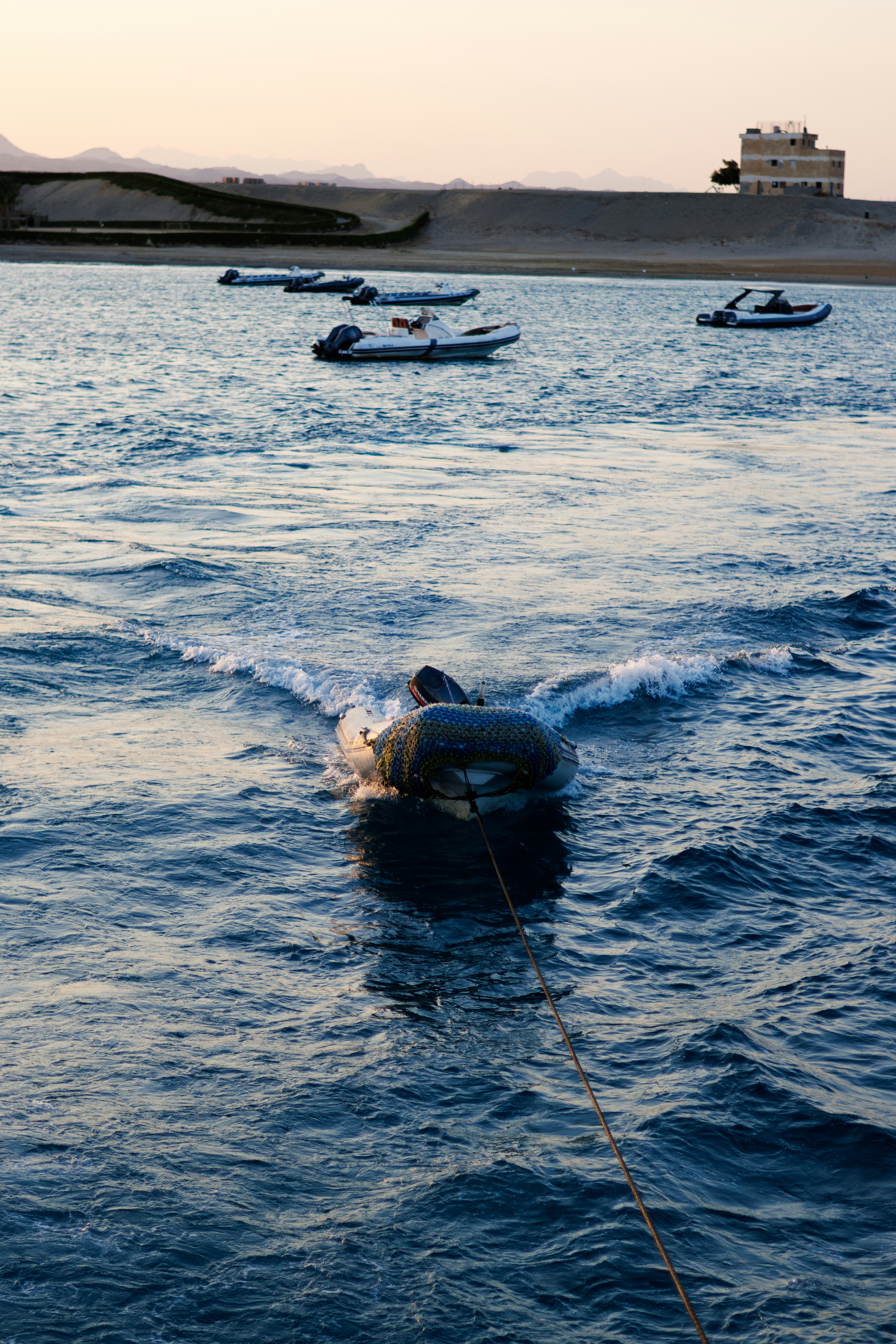 Uniformed officers on a patrol boat approaching and boarding a smaller vessel at sea