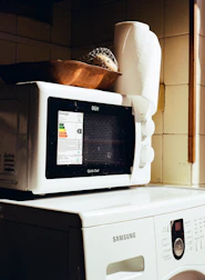 Microwave oven stacked on top of a washing machine.