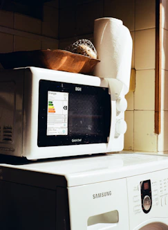 Microwave oven stacked on top of a washing machine.