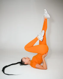 Woman in orange activewear performing yoga pose on floor