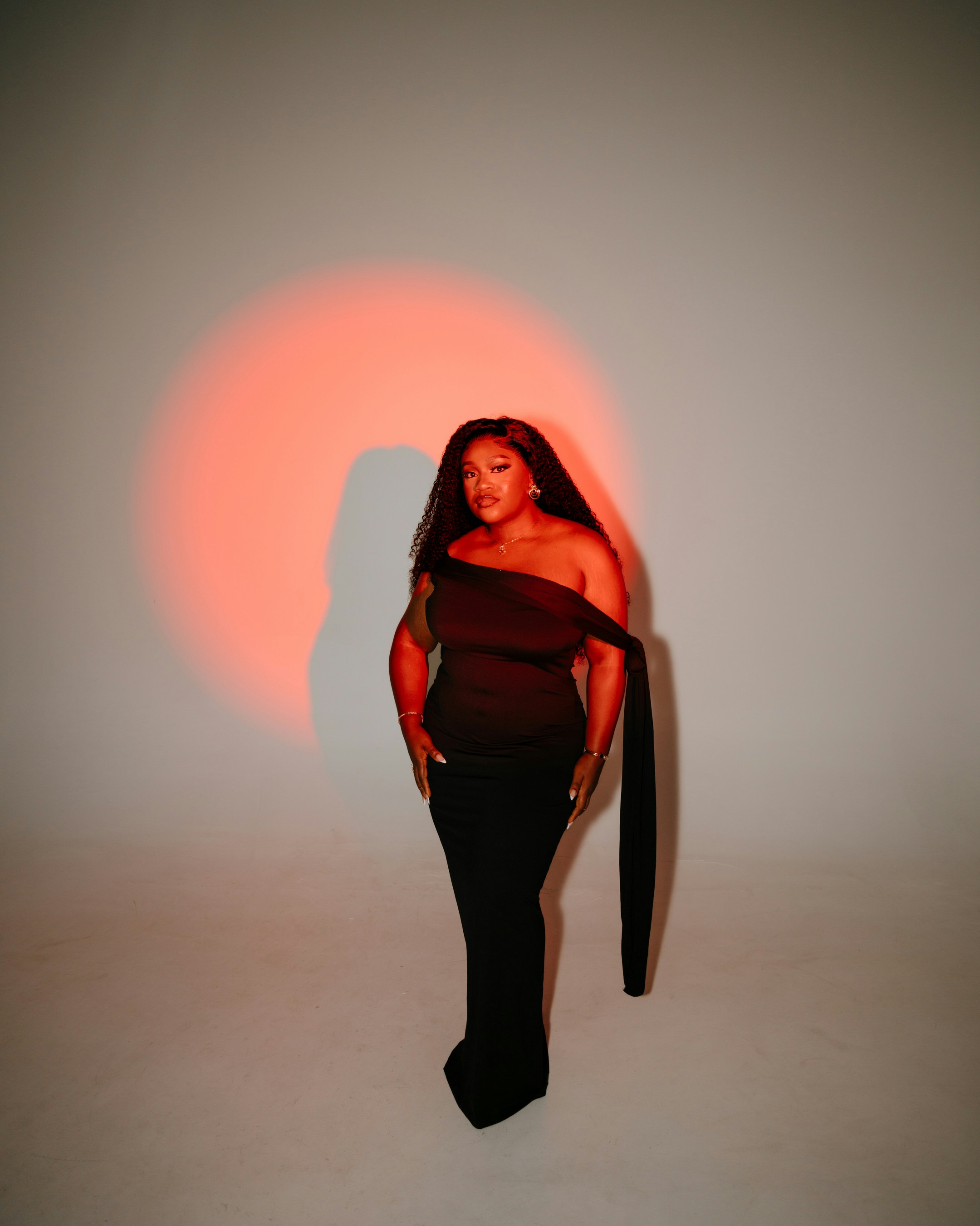 A woman in a black dress with a red spotlight.