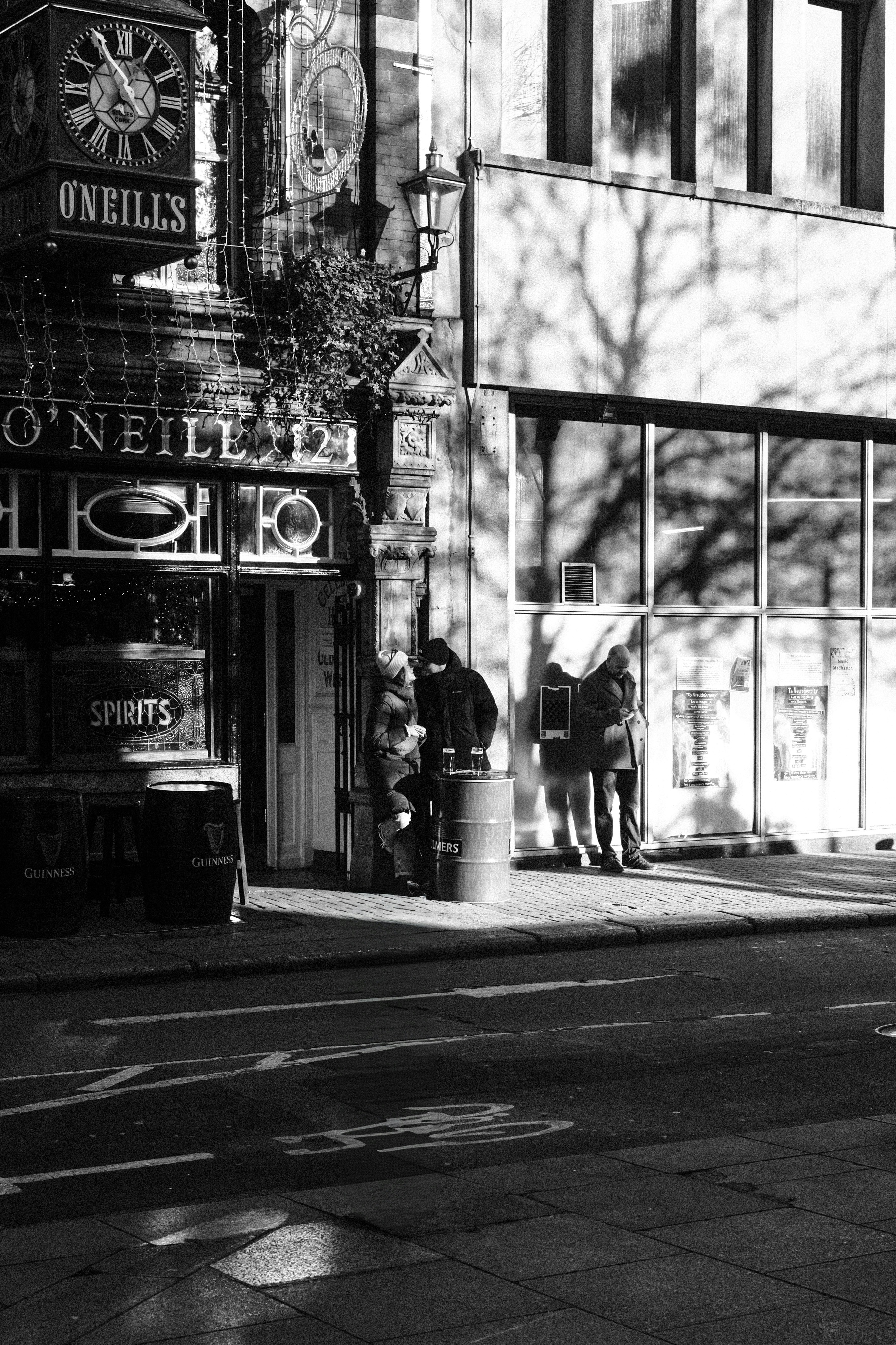 People stand outside o'neills pub on a sunny day.