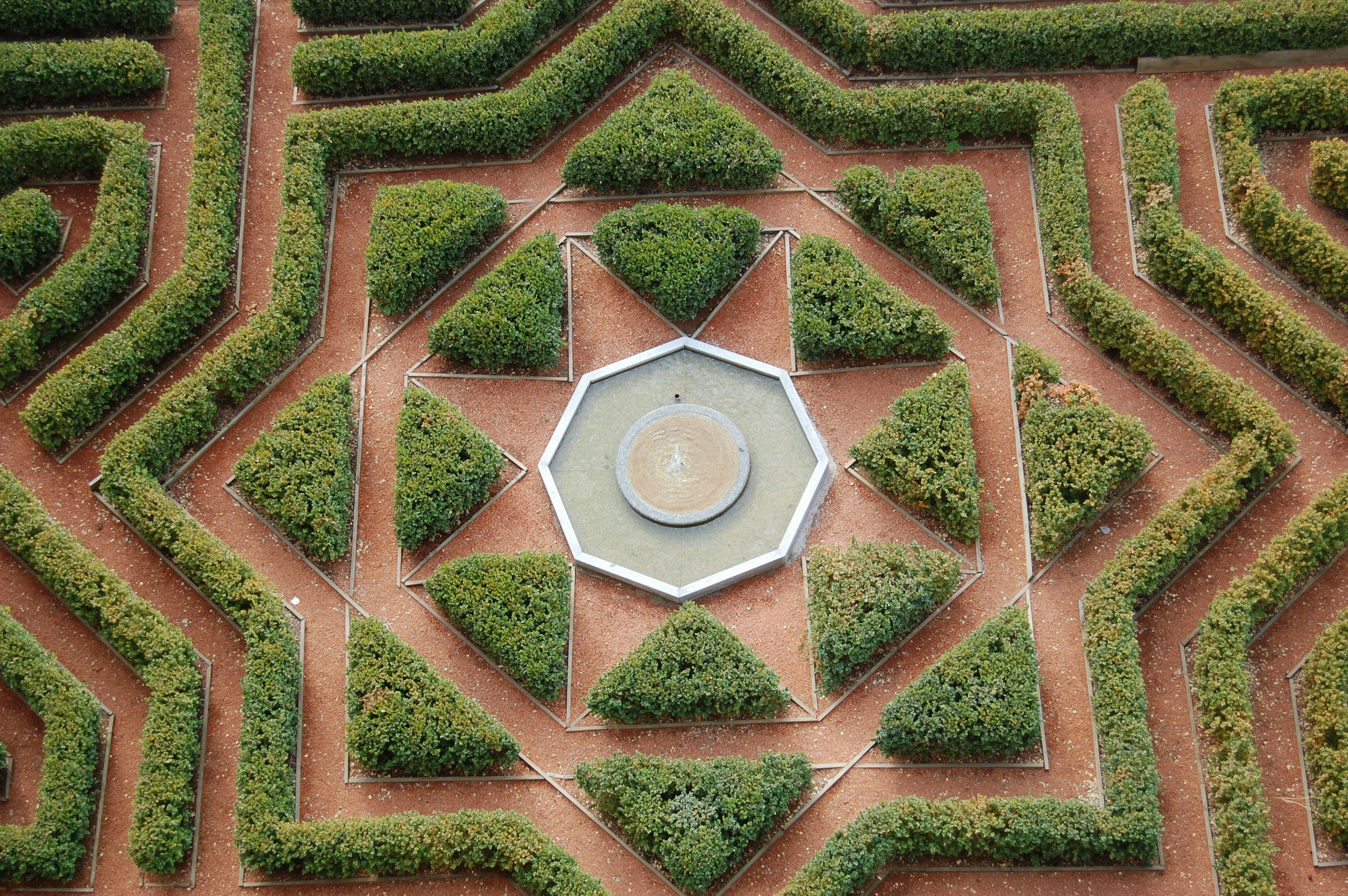 Laberinto geométrico de setos con fuente central y patrón de estrellas