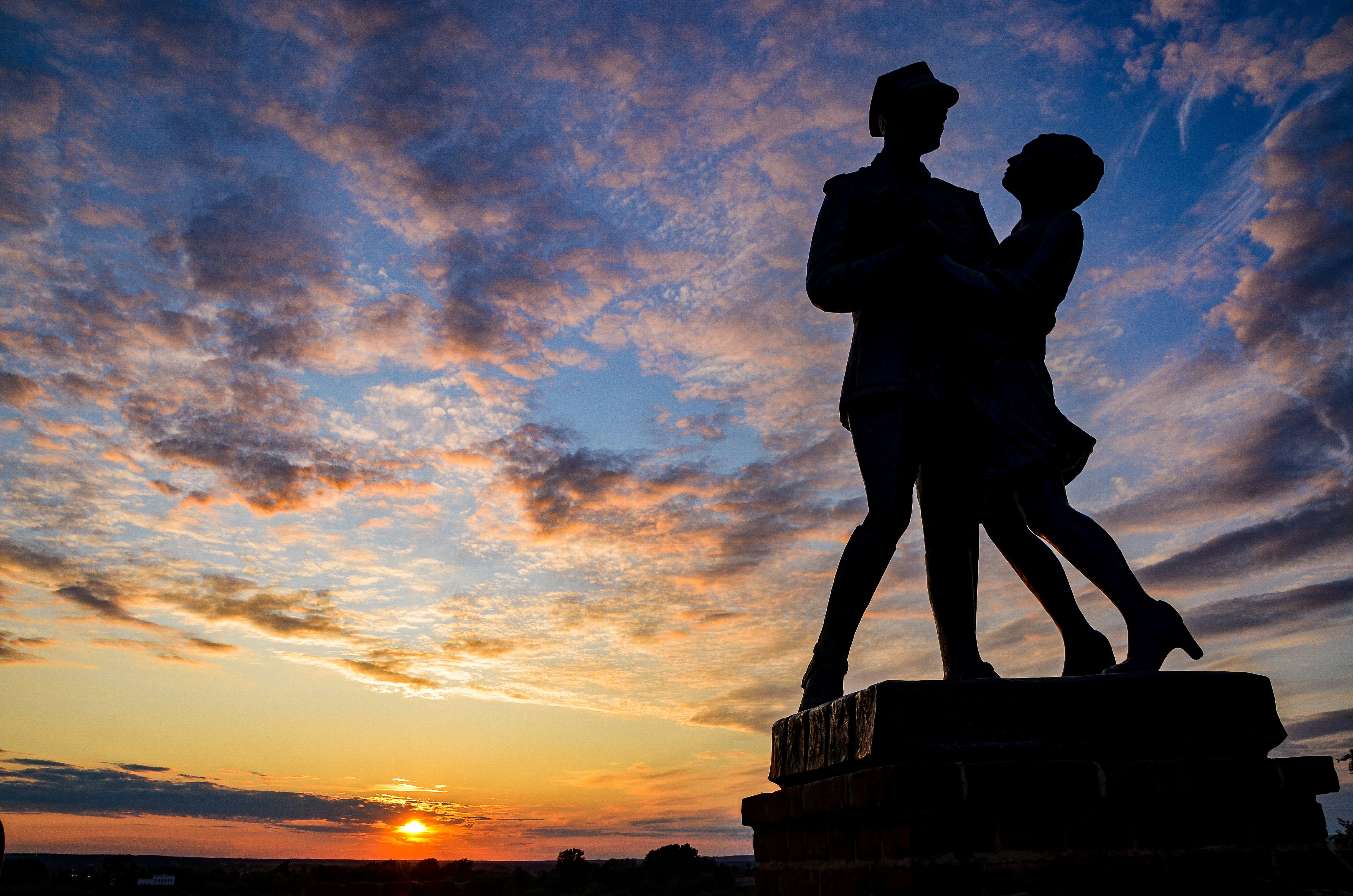 Silhouette di coppia che balla contro un drammatico cielo al tramonto