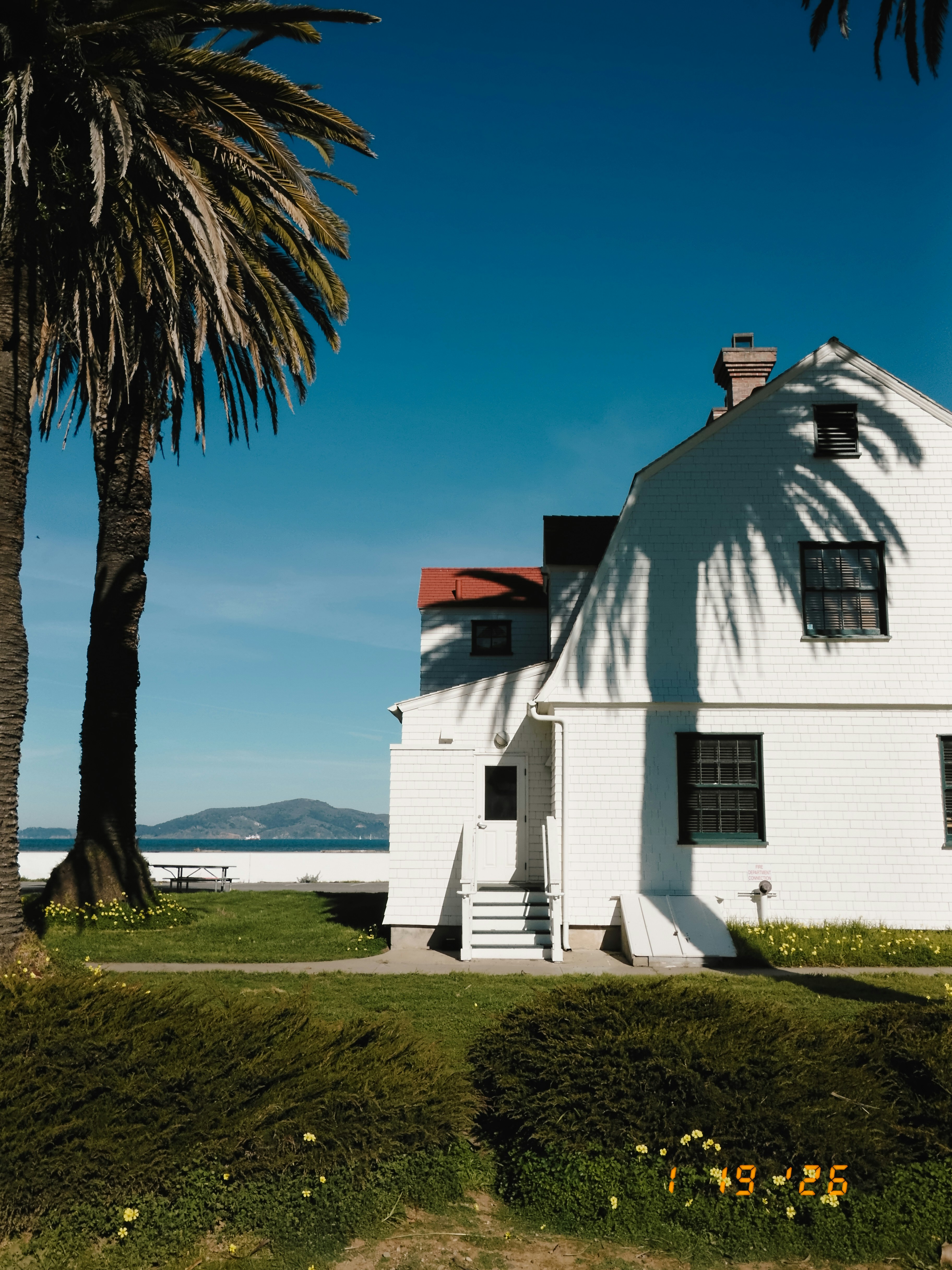 White building with palm trees and ocean view.