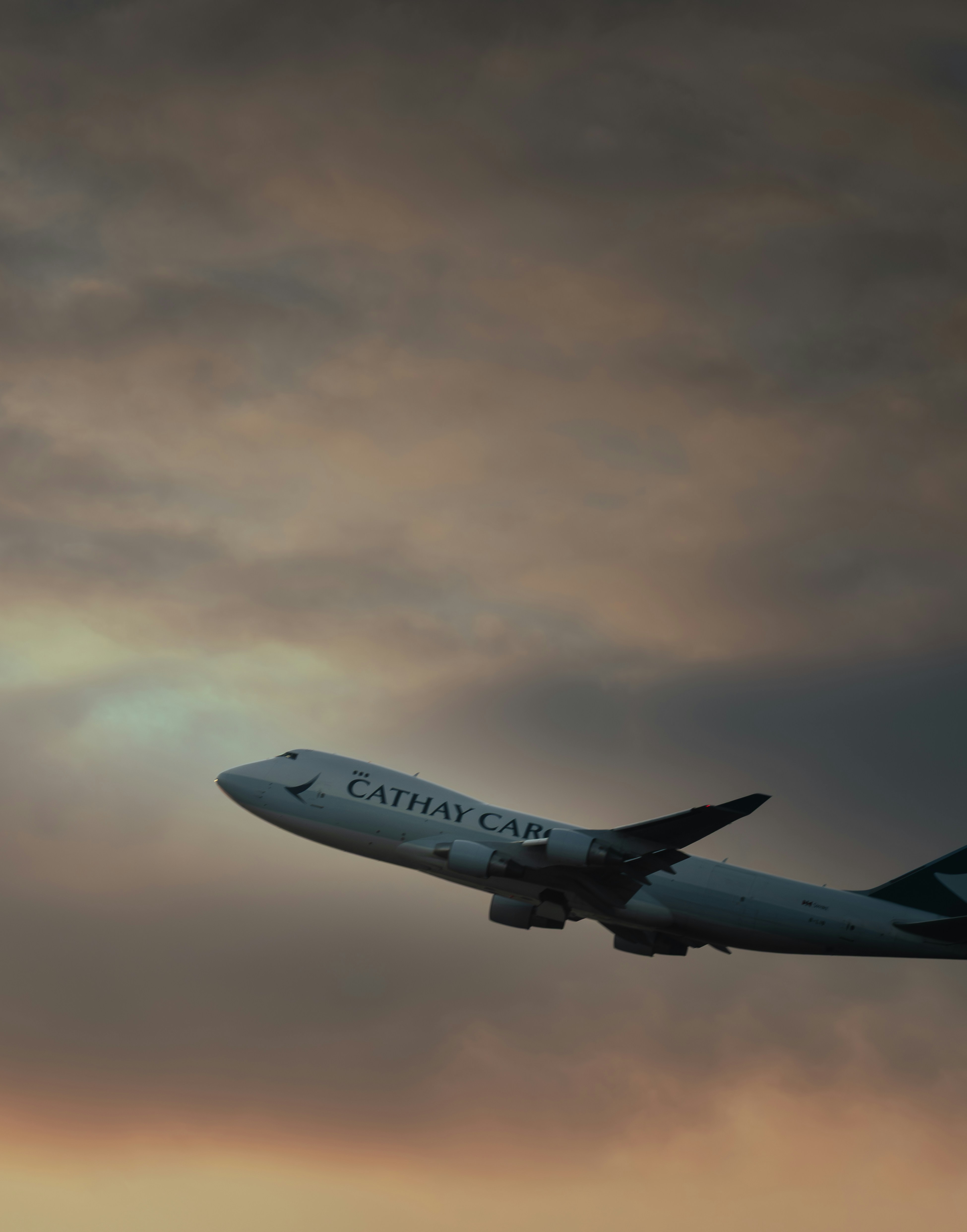 A cathay pacific airplane ascending into a cloudy sky.