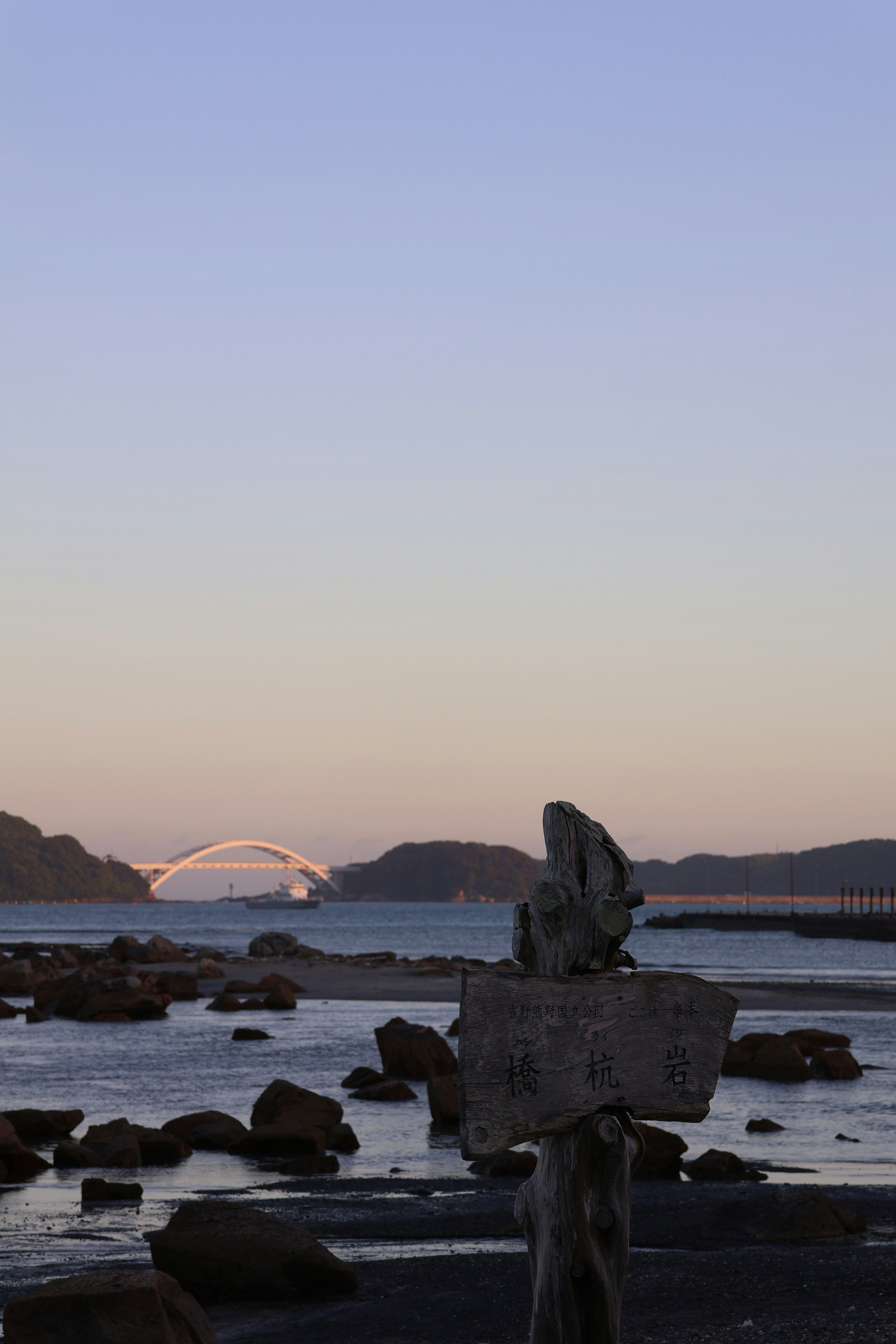Bridge over water with rocks and a signpost
