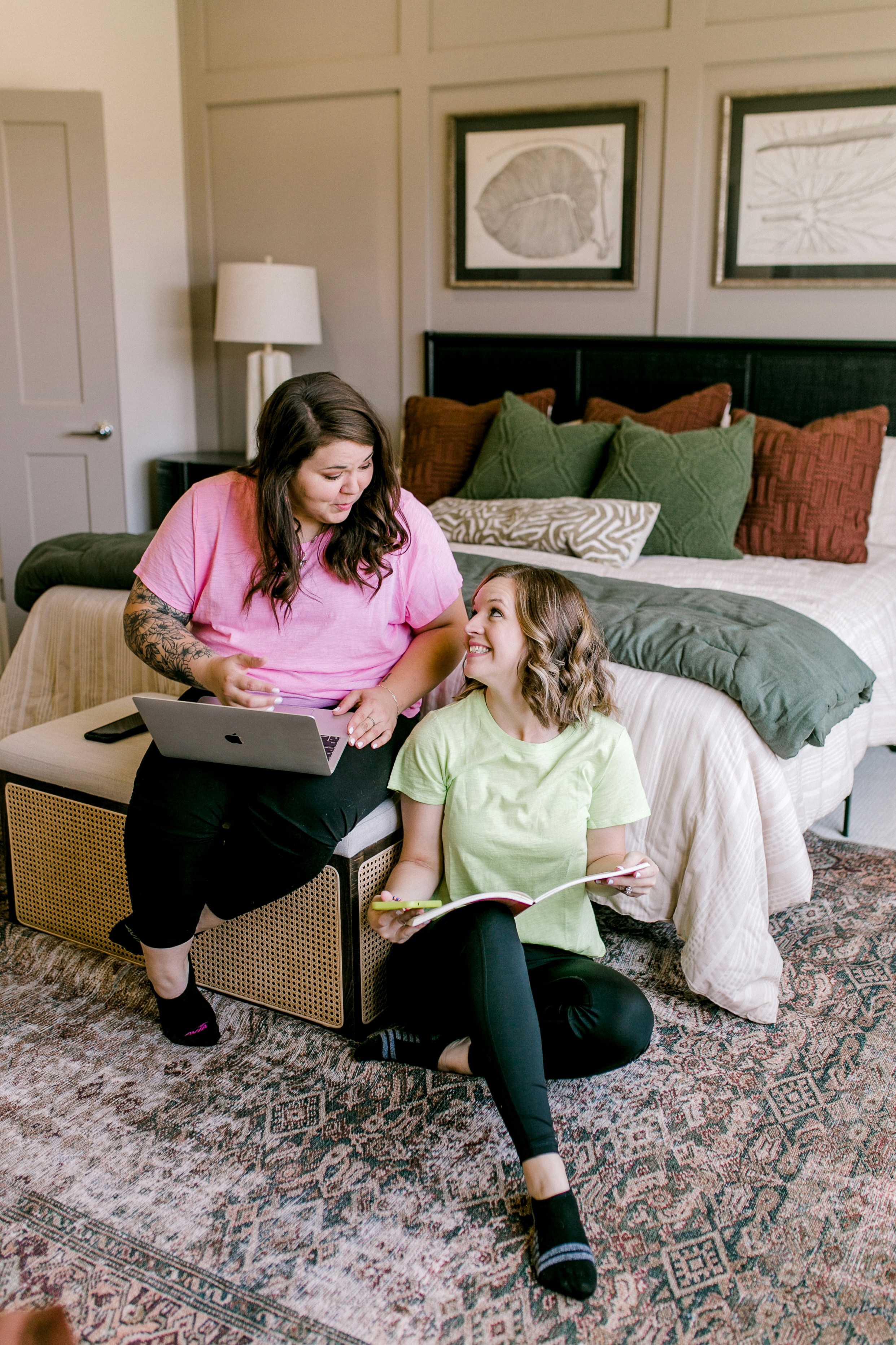 Two women working on a laptop and book.